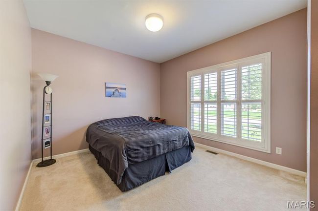 The fourth bedroom has a wall of windows with wood plantation shutters and a closet. | Image 27