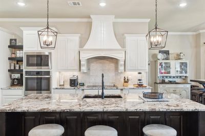 A chefs dream. Beautiful hood, oversized granite island, double oven and cabinets galore. | Image 2