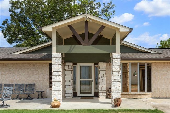 The rustic covered front porch and stone columns framing the front entry elevates the entrance of this home | Image 14