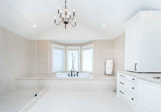 Bathroom with a tub to relax in, ornamental molding, lofted ceiling, and a chandelier | Image 25