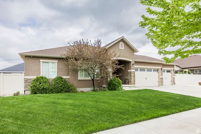 Single story home featuring stone siding, stucco siding, an attached garage, and driveway | Image 41