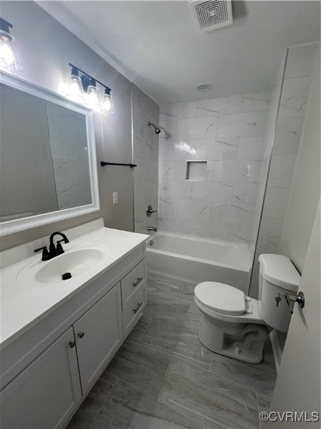 Bathroom with toilet, bathing tub / shower combination, visible vents, marble finish floor, and vanity | Image 12