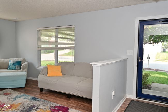living area with wood finished floors, a textured ceiling, and baseboards | Image 4