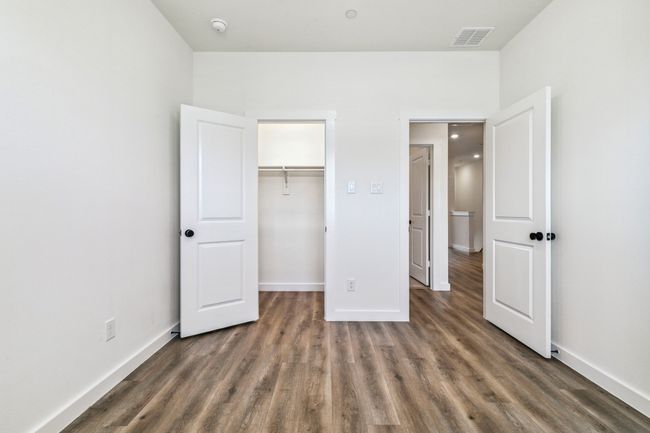 Unfurnished bedroom with wood finished floors, baseboards, a spacious closet, and a closet | Image 27