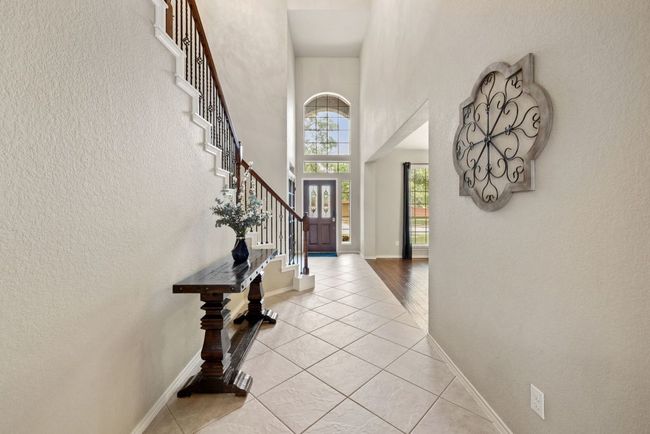 Foyer with stairway, light tile patterned floors, a high ceiling, and a textured wall | Image 4