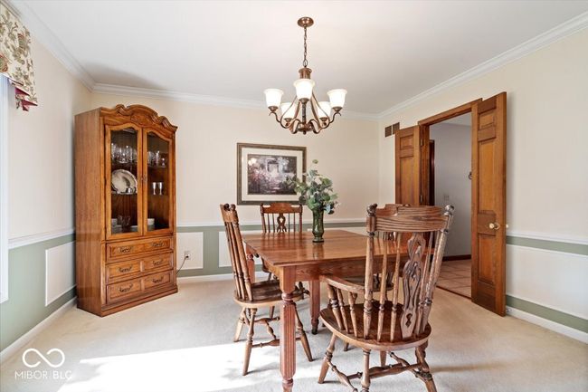 dining space with a chandelier, crown molding, and light colored carpet | Image 19