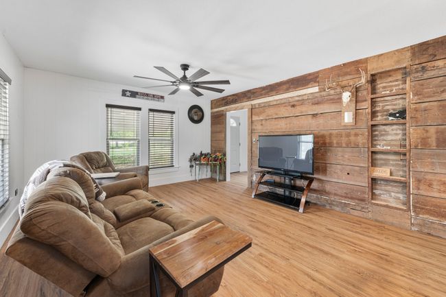 Living room featuring wooden walls, wood finished floors, and a ceiling fan | Image 4