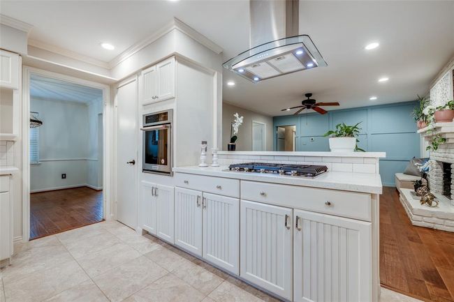 Spacious kitchen with white cabinets, travertine tiled floor, Kitchen Aid Gas cook top & Kitchen Aid single Oven, vent, pantry, recessed lighting, door through to study/formal living room/dining room | Image 14