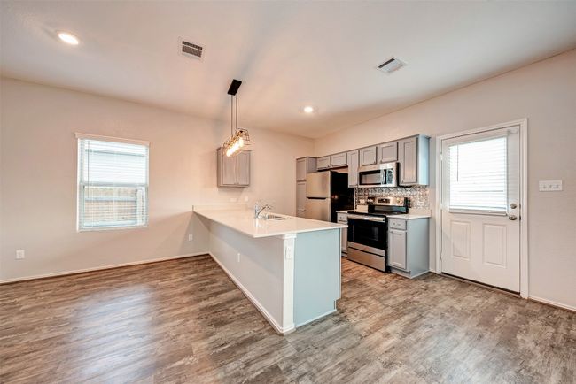Kitchen with stainless steel appliances, gray cabinetry, wood finished floors, a sink, and recessed lighting | Image 11