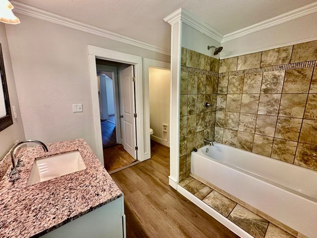 Full bath featuring wood finished floors, vanity, crown molding, and shower / tub combination | Image 8