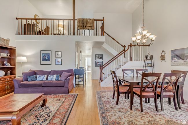 Living area featuring a chandelier, light wood-type flooring, a towering ceiling, and stairs | Image 11
