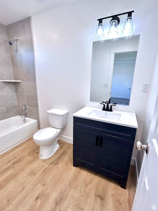 Bathroom featuring vanity, shower / bathtub combination, toilet, baseboards, and wood finished floors | Image 16