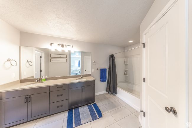 Full bathroom featuring double vanity, shower/bath combo, and attached walk-in closet. | Image 14