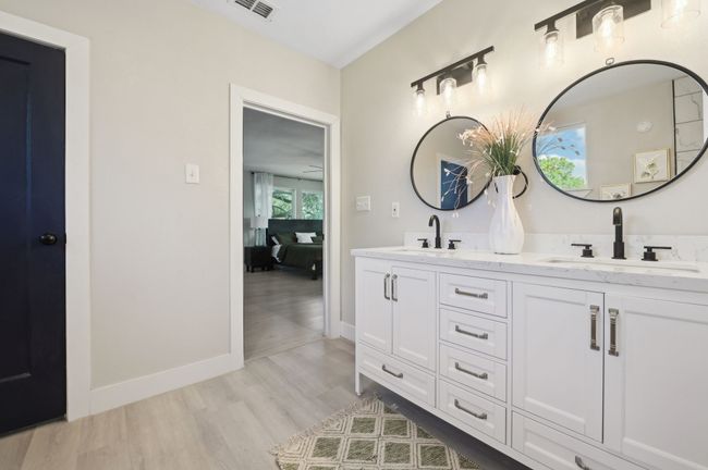 Ensuite bathroom featuring double vanity, wood finished floors, and baseboards | Image 23