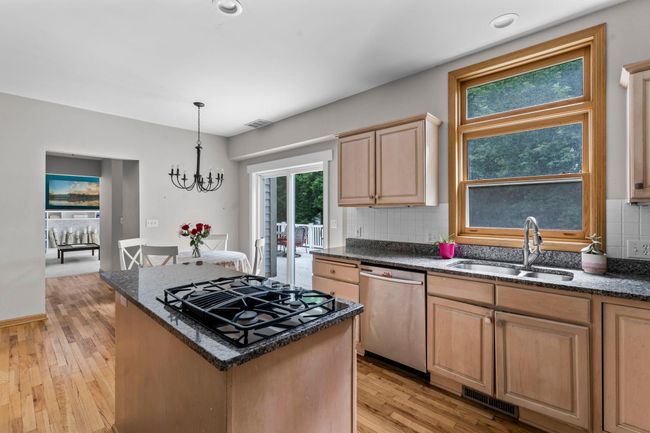 The heart of the home is the beautifully designed kitchen, featuring sleek stainless steel appliances, including double wall ovens and a gas cooktop, a center island for prep and gathering, and a stylish tile backsplash. | Image 7