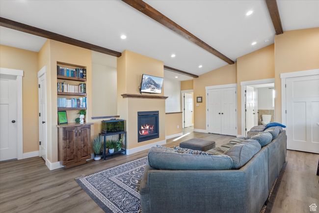 Living room with lofted ceiling with beams, baseboards, wood finished floors, and a glass covered fireplace | Image 11