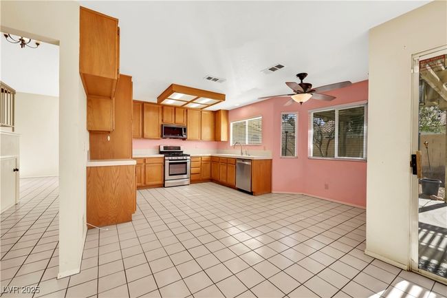 Kitchen featuring light tile patterned floors, visible vents, stainless steel appliances, and light countertops | Image 13