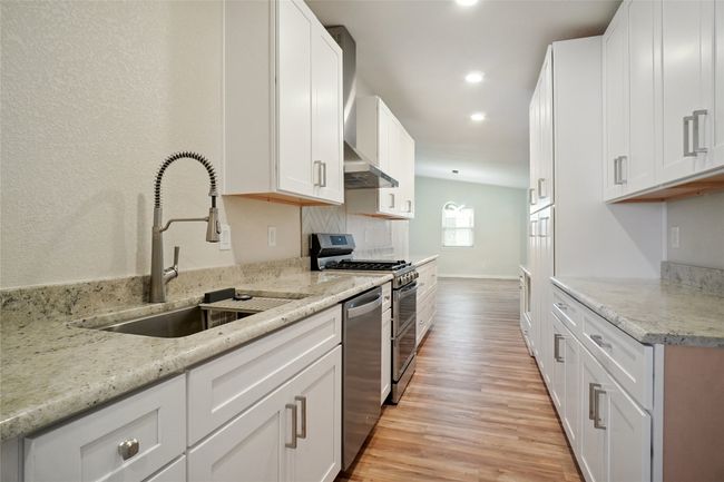 Stunning galley kitchen with custom wood cabinetry, granite countertops, built-in pantry, and upgraded fitxures. | Image 8