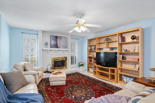 Tiled living room with ceiling fan, a textured ceiling, a fireplace, and a healthy amount of sunlight | Image 5