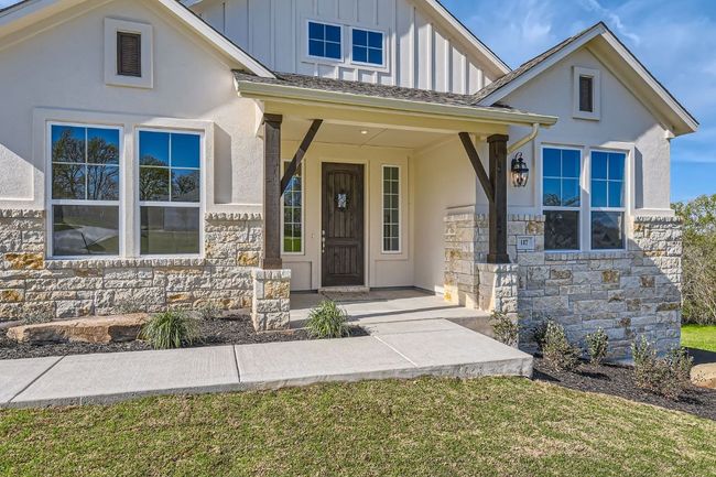 View of front of home featuring board and batten siding, covered porch, stone siding, and stucco siding | Image 6