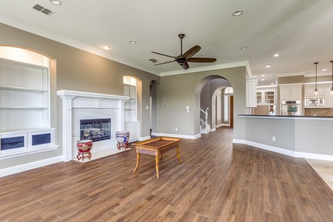 Living room featuring ceiling fan, a glass covered fireplace, ornamental molding, and recessed lighting | Image 11