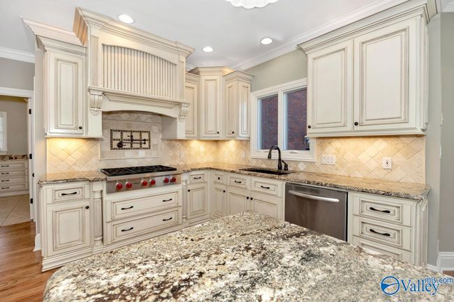 Wood flooring, wood cabinetry, kitchen island with bar seating, recessed lighting | Image 13