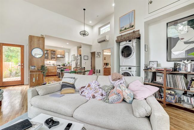 Living room with light wood-style flooring, stacked washer and dryer, an AC wall unit, and a wealth of natural light | Image 32