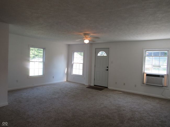 foyer entrance featuring carpet, healthy amount of natural light, ceiling fan, a textured ceiling, and cooling unit | Image 7