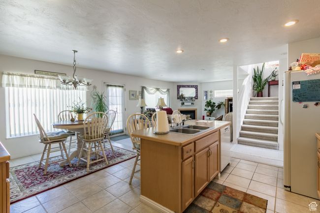 Kitchen featuring recessed lighting, white appliances, a kitchen island with sink, a fireplace, and a sink | Image 11