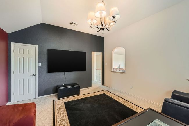 Carpeted living room featuring vaulted ceiling and a chandelier | Image 30