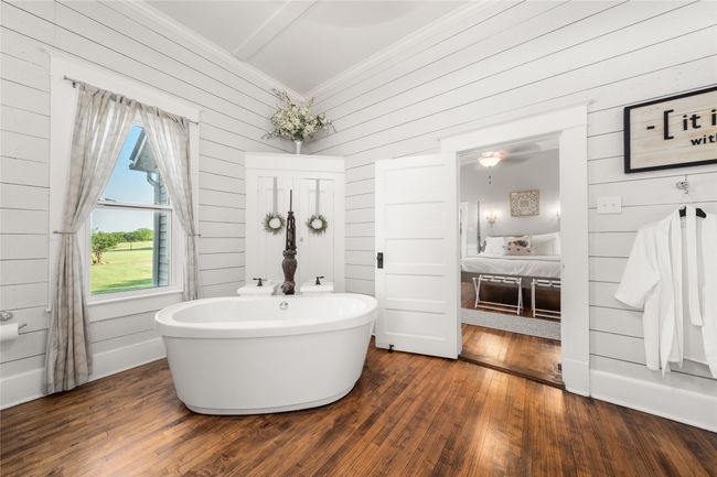 Full bathroom featuring wooden walls, a freestanding bath, wood finished floors, crown molding, and a ceiling fan | Image 19
