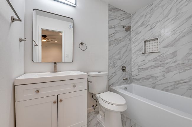 Full bath featuring a ceiling fan, vanity, marble finish floor, shower / tub combination, and toilet | Image 16