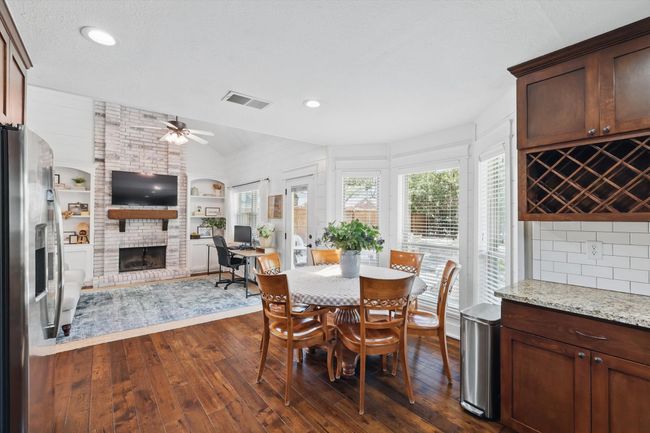 Dining space with dark wood-type flooring, vaulted ceiling, ceiling fan, a brick fireplace, and built in shelves | Image 8