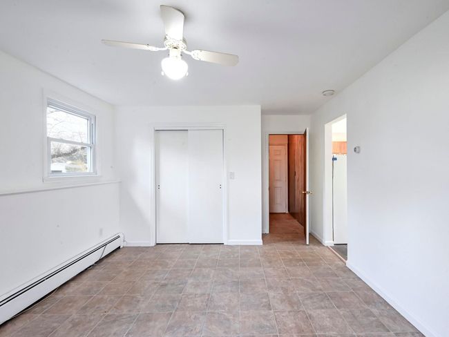 Unfurnished bedroom featuring ceiling fan, a closet, and a baseboard radiator | Image 16