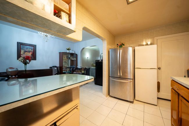 Kitchen with freestanding refrigerator, arched walkways, light tile patterned flooring, and light countertops | Image 14