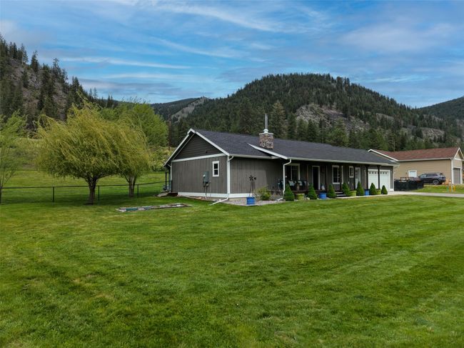 Back of property featuring a mountain view, a garage, a chimney, driveway, and covered porch | Image 34