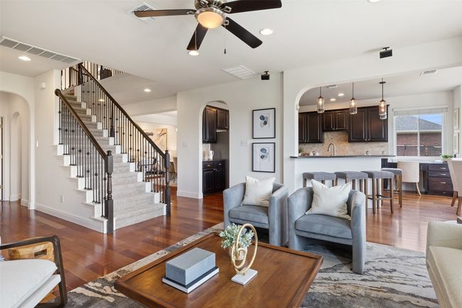 Living area featuring arched walkways, dark wood-style flooring, recessed lighting, stairway, and a ceiling fan | Image 11