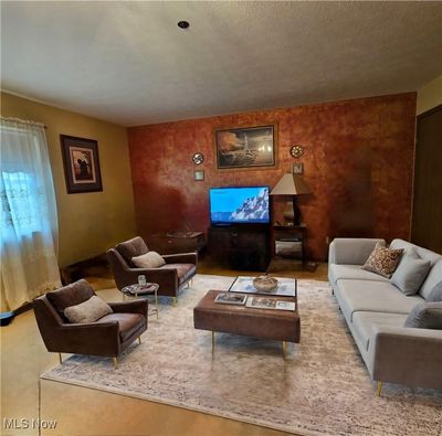 Unfurnished living room with a chandelier, a textured ceiling, and light carpet | Image 2