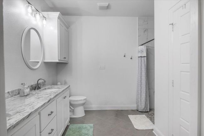 Bathroom with visible vents, toilet, vanity, baseboards, and curtained shower | Image 18
