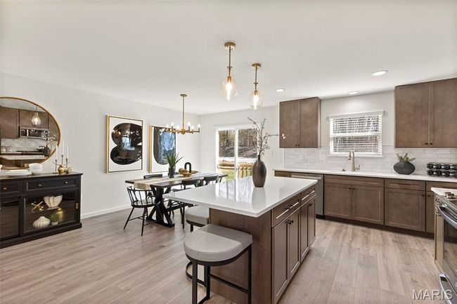 Kitchen with appliances with stainless steel finishes, backsplash, a sink, light countertops, and light wood-style flooring | Image 7