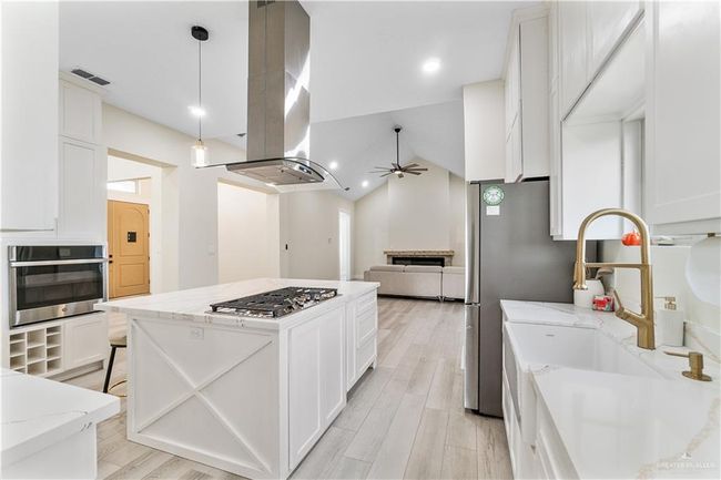 Kitchen with white cabinets, vaulted ceiling, appliances with stainless steel finishes, light stone counters, and ceiling fan | Image 19