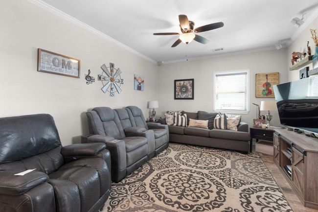 Living room with visible vents, ceiling fan, and crown molding | Image 9
