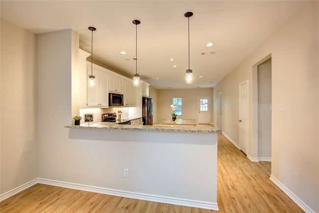 Kitchen featuring appliances with stainless steel finishes, light wood-style floors, white cabinets, a peninsula, and recessed lighting | Image 6