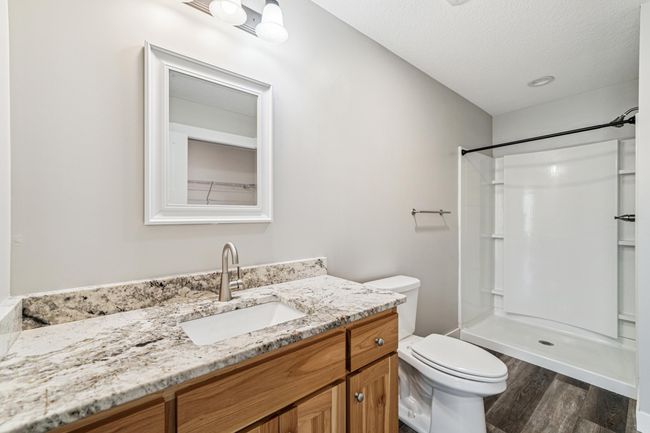 Private, primary 3/4 bathroom with LVP flooring, birch cabinet and granite vanity top. | Image 15