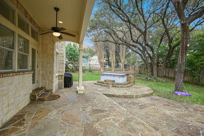 View of patio with entry steps, ceiling fan, a fenced backyard, a grill, and a hot tub. | Image 34