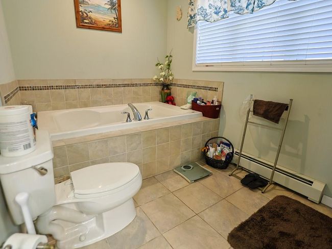 Bathroom with a garden tub, toilet, tile patterned floors, and baseboard heating | Image 26