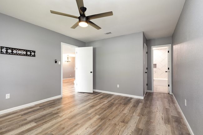 Unfurnished bedroom featuring wood finished floors, baseboards, ensuite bathroom, and a ceiling fan | Image 29