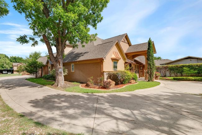 View of property exterior featuring stucco siding, curved driveway, and roof with shingles | Image 5