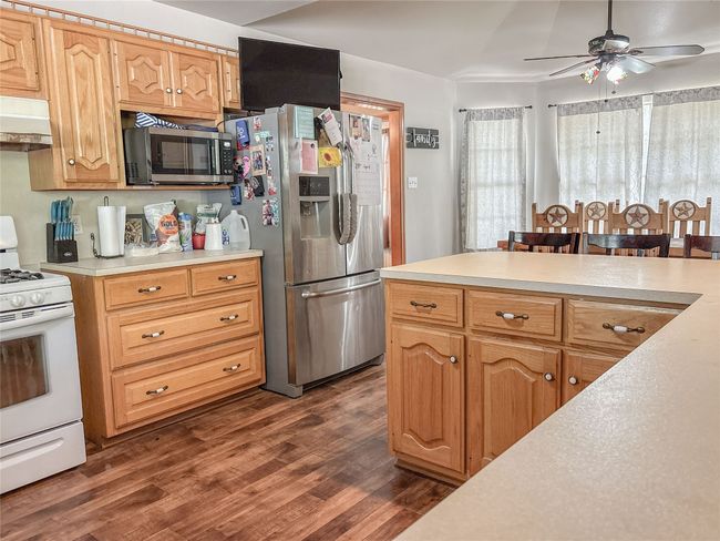 Kitchen with light countertops, stainless steel appliances, a ceiling fan, and dark wood-type flooring | Image 8