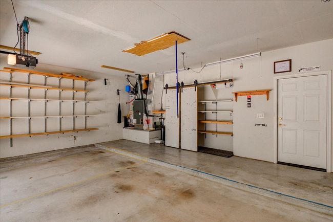 Garage featuring a garage door opener and built in storage | Image 37